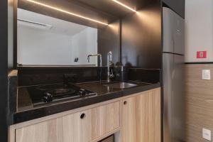 una cucina con lavandino e frigorifero in acciaio inossidabile di Housi Paulista a San Paolo