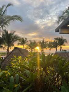 a view of a beach with palm trees and the sunset at San Carlos Surf Resort & Eco Lodge in San Carlos