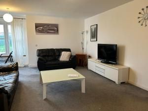 a living room with a couch and a flat screen tv at Spacious Modern Apartment in St. Andrews