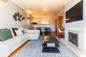 a living room with a white couch and a fireplace at Telheiras Premium by Homing in Lisbon