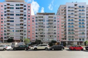 a parking lot with cars parked in front of a pink building at Telheiras Premium by Homing in Lisbon