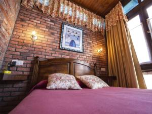 1 dormitorio con cama y pared de ladrillo en La Casona de Sobrepiedra en Sobrepiedra