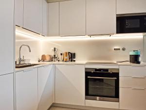 cocina con armarios blancos, fregadero y horno en Bayline Condominium - Heated indoor Swimming pool - SPA - By Bedzy, en Armação de Pêra
