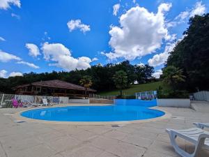 uma piscina com cadeiras e um céu azul em Le chalet Roy em Mauroux