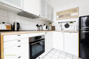eine Küche mit weißen Schränken und einem schwarzen Backofen in der Unterkunft PINEAPPLE APARTMENTS - Dresden Zwinger - 55qm in Dresden