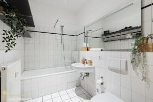 een witte badkamer met een wastafel en een bad bij Pineapple Apartments Dresden Zwinger in Dresden