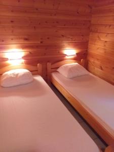 2 letti in una camera con pareti e luci in legno di Le chalet Magalli a Mauroux