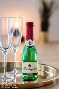 eine grüne Flasche auf einem Tablett mit zwei Gläsern in der Unterkunft PINEAPPLE APARTMENTS - Dresden Zwinger - 55qm in Dresden