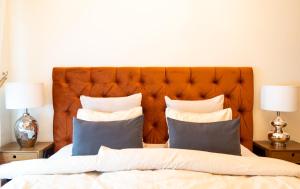 uma cama com cabeceira laranja e almofadas em Design apartment em Liepāja