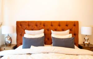 a bed with a orange headboard and pillows on it at Design apartment in Liepāja