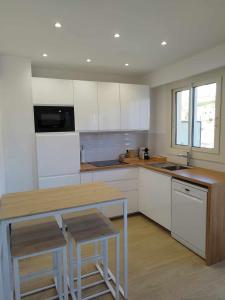 a kitchen with white cabinets and a wooden counter top at Appartement moderne refait à neuf - 4 couchages - MENTON in Menton