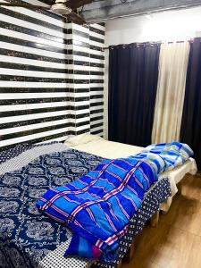 a bedroom with a bed with blue comforter at Shyam Sadan Guest House in Vrindāvan