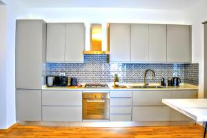 a white kitchen with white cabinets and a sink at VUEL SEA VIEW HOUSE -10 Minutes from the Airport Fiumicino in Fiumicino