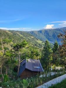 una pequeña cabaña en el bosque con montañas en el fondo en Ecoverso Cabañas del bosque, en Medellín