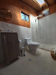 uma casa de banho com um WC, um chuveiro e uma janela. em Ecoverso Cabañas del bosque em Medellín
