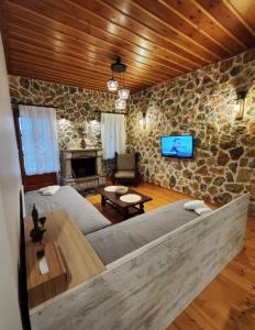 a living room with a couch and a stone wall at Heart of Proussos in Prousós