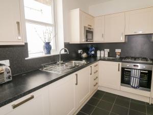 a kitchen with white cabinets and a sink and a window at Haven Cottage in Kirkcudbright