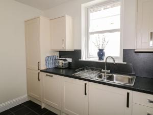 une cuisine avec des armoires blanches, un évier et une fenêtre dans l'établissement Haven Cottage, à Kirkcudbright 19 autres photos