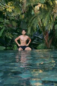 un hombre sentado en el agua en una piscina en The Falls at Manuel Antonio en Manuel Antonio