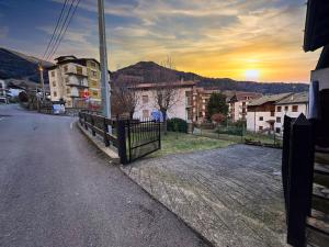 a fence on the side of a street with a sunset at residenza piccolo diamante a 300m dal centro in Borno
