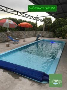 a large swimming pool with an open umbrella and an umbrella at Refugio Verde Zen in Dois Vizinhos