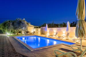 a swimming pool with chairs and umbrellas at night at Villa Jerkovic in Metković