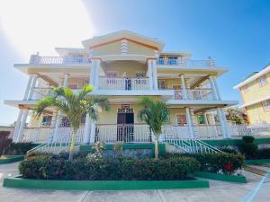 une grande maison avec des palmiers en face de celle-ci dans l'établissement J&G Villa Hotel, à Cap-Haïtien