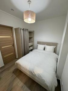 - une chambre avec un grand lit blanc et un lustre dans l'établissement Appartement moderne au centre-ville, à Saint-Denis