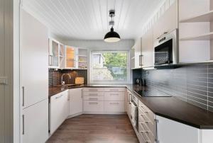 eine Küche mit weißen Schränken und einem Fenster in der Unterkunft Centrum apartment in Ålesund