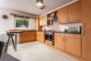 a kitchen with wooden cabinets and a table at Walker Suite No 60 - Donnini Apartments in Kilmarnock