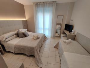 1 dormitorio con 2 camas y espejo en Hotel Stefan Room & Breakfast, en Gatteo a Mare