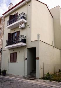 a white building with a door and a balcony at MARON ΙΙ με τζάκι in Kalavrita