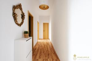 einen Flur mit weißen Wänden und Holzböden in der Unterkunft PINEAPPLE APARTMENTS - Dresden Zwinger - 55qm in Dresden