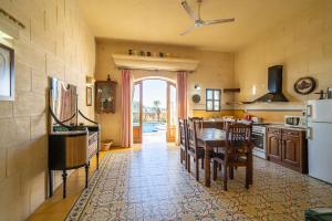 cocina con mesa, sillas y nevera en 3 Bedroom Holiday Home with Large Private Pool and Views, en Xewkija