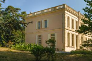 une grande maison blanche avec des arbres devant elle dans l'établissement Maison d'hôtes - Villa Les Pins - Lempaut, à Lempaut