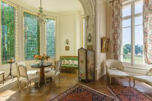 - un salon avec une table, des chaises et des fenêtres dans l'établissement Maison d'hôtes - Villa Les Pins - Lempaut, à Lempaut