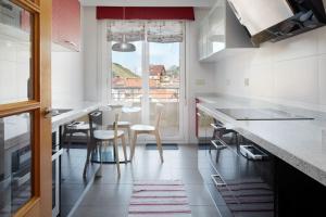 a kitchen with white counters and a table and chairs at Ondartxo III - ONGI ETORRI in Zumaia