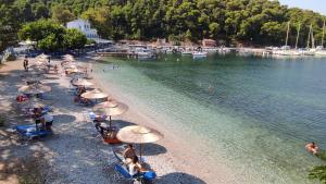 a group of people sitting on a beach with umbrellas at Kallisti Seaside Studios Skopelos in Agnontas
