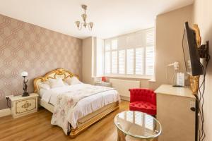 a bedroom with a bed and a red chair at Katolondonhaus in Mitcham