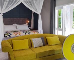 a yellow couch in a bedroom with a bed at Green Elephant in Lilongwe
