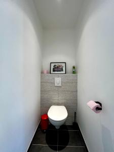a bathroom with a white toilet and a red trash can at Maisonnette 2 pers tout confort près de Paris in Bobigny