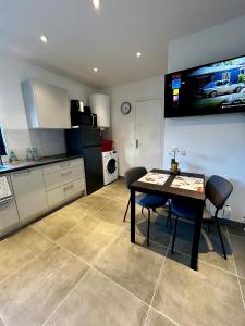 uma cozinha com mesa e cadeiras e uma televisão em Maisonnette 2 pers tout confort près de Paris em Bobigny