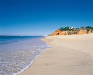 a beach with the ocean and a blue sky at Dunas Douradas Beach Club in Vale do Lobo