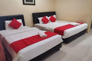 2 camas en una habitación con sábanas rojas y blancas en Langkawi Tok Jah Guest House Pantai Cenang en Pantai Cenang