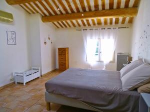 sypialnia z dużym łóżkiem i oknem w obiekcie Logement charme provençal w mieście Cabannes
