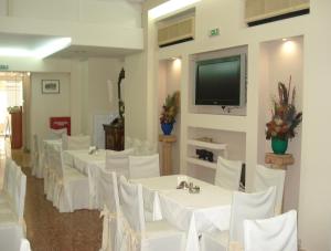 a room with white tables and white chairs and a flat screen tv at Hotel Solomou Athens in Athens