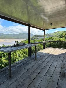 eine Holzterrasse mit einem Tisch darüber in der Unterkunft Blue Lagoon Cottage in Umngazana