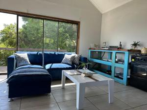 a living room with a blue couch and a table at Blue Lagoon Cottage in Umngazana
