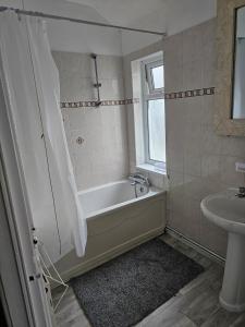 a bathroom with a bath tub and a sink at VIkky'S BnB in Birmingham