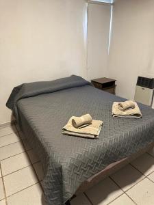Una cama con dos toallas encima. en ArquiArts Casa-Departamento en Barrio Huerto del Sol en 